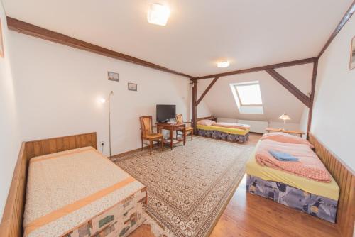 a room with two beds and a desk and a tv at Pension U kostela in Český Brod