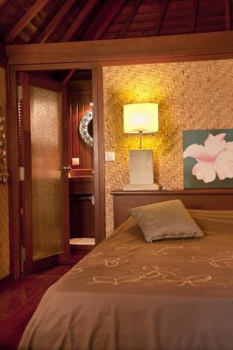 a bedroom with a bed and a lamp on a wall at Robinson's Cove Villas in Papetoai