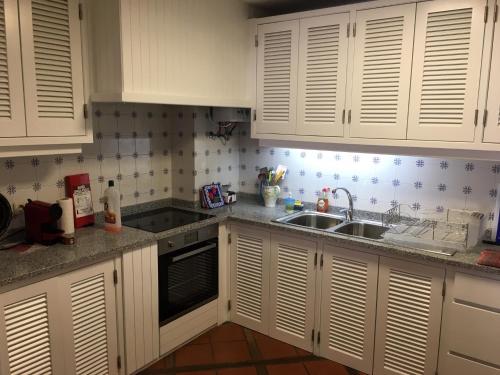 a kitchen with white cabinets and a sink at Trajadinha - Casa da Travessa in Caminha