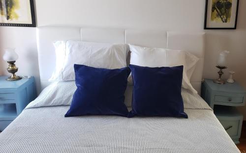 a bed with two blue pillows and two blue tables at Trajadinha - Casa da Travessa in Caminha