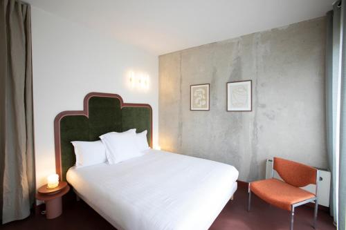 une chambre avec un grand lit et une chaise dans l'établissement Joie Paris Bargue, à Paris