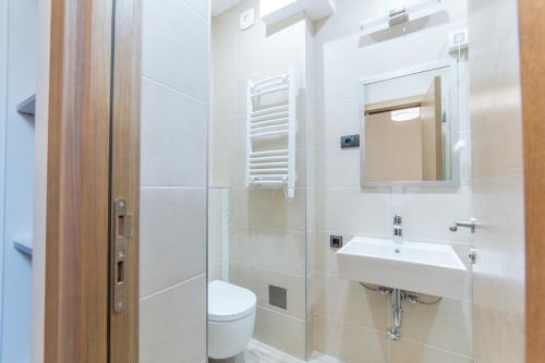 a white bathroom with a toilet and a sink at M House Belgrade Residence in Belgrade