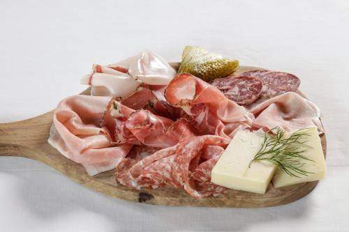 a plate of meats and cheese on a wooden spoon at Albergo Aurora in Vignola