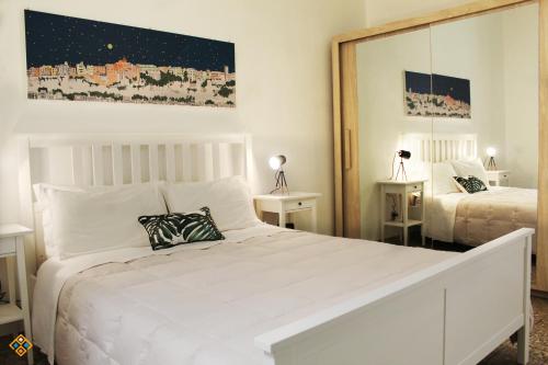 a bedroom with a white bed and a large mirror at Sa Domu de Ajaja Apartments in Cagliari