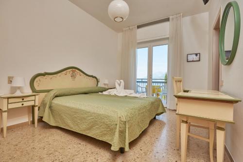 1 dormitorio con cama verde y balcón en Hotel Villa Orizzonte, en Malcesine