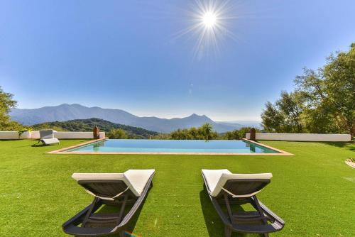 a swimming pool with two lounge chairs in the grass at Villa Bella Vista in Gaucín