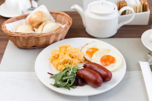 a plate of food with sausage and eggs and bread at Hotel Kramer in Opava