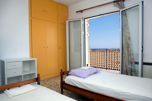 a bedroom with two beds and a large window at Family House in Lakones in Paleokastritsa