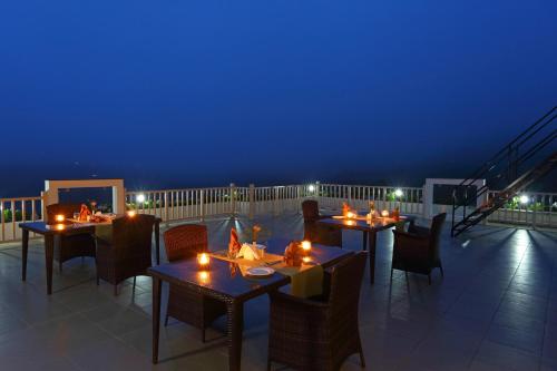 a restaurant with tables and chairs on a balcony at night at Chandys Windy Woods Munnar in Munnar