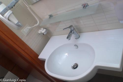 uma casa de banho com um lavatório branco e um telefone em Villaggio Turistico La Mantinera - Appartamenti de Luxe em Praia a Mare