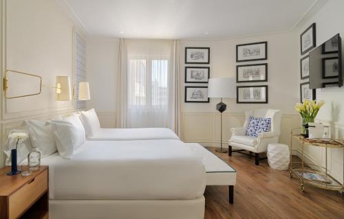 a white bedroom with a white bed and a chair at H10 Duque de Loule in Lisbon