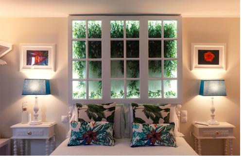 a bedroom with a window above a bed with pillows at My Bed in pico in Madalena