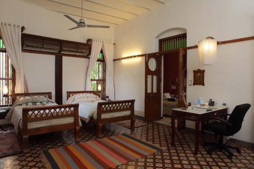 a bedroom with two beds and a table and chairs at The House of MG-A Heritage Hotel, Ahmedabad in Ahmedabad