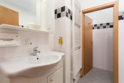 a white bathroom with a sink and a shower at Apartmány Kramer in Opava