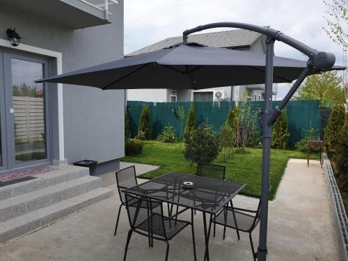 a table and chairs under an umbrella on a patio at VillaGrey Tunari in Tunari