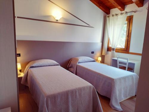 two beds in a hotel room with a window at Agriturismo le Colonie in Preganziol