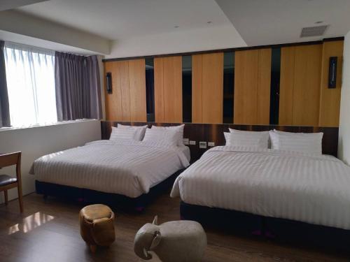 Habitación de hotel con 2 camas con sábanas blancas en Lantan Fanyue Inn en Chiayi