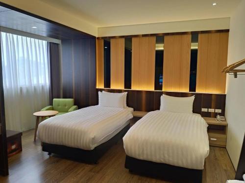a hotel room with two beds and a chair at Lantan Fanyue Inn in Chiayi City