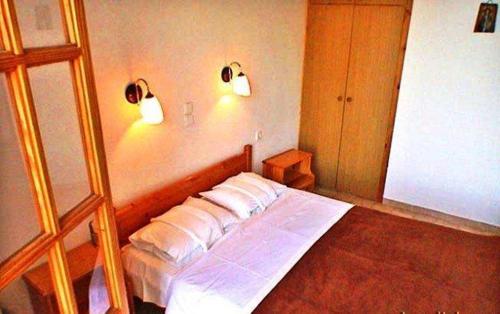 a bedroom with a bed with two lights on the wall at Diamont Studios in Agia Galini