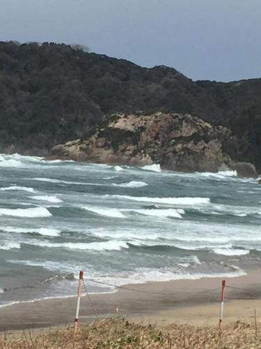 a beach with a rocky island in the ocean at Iwamino Oyado lucere in Uradome