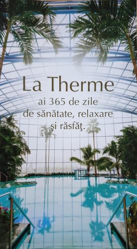 a sign above a swimming pool with palm trees at VillaGrey Tunari in Tunari