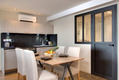 a kitchen with a wooden table and white chairs at Hôtel & Spa Les Mouettes in Argelès-sur-Mer