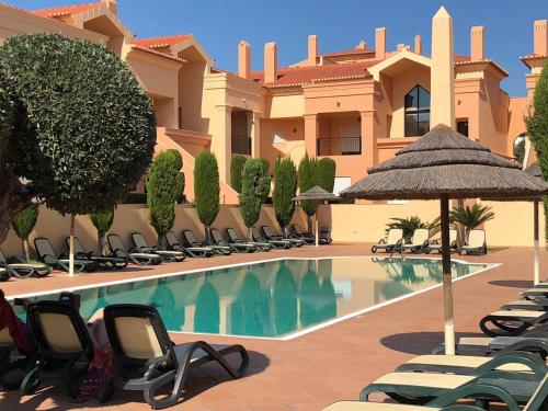 Villa con piscina con sillas y sombrilla en Praia Da Luz Apartment en Luz