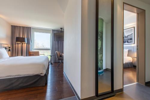 a hotel room with a bed and a mirror at Radisson Hotel Zurich Airport in Rümlang