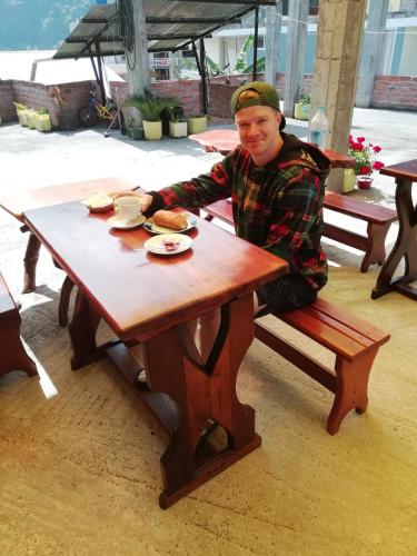 a man is sitting at a picnic table at Hostal La Casa Amarilla City in Baños