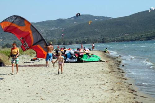 a group of people on a beach flying kites at Tsina’s apartments in Ágios Nikólaos