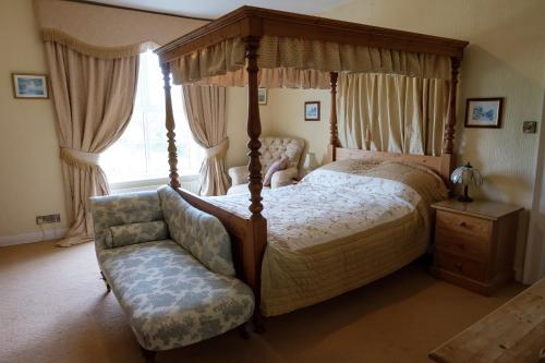 a bedroom with a canopy bed and a chair at Ford Down Farm B&B in South Molton