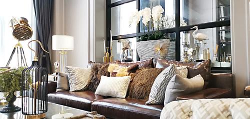 a living room with a brown leather couch with pillows at SN Connx - SHA Plus in Pattaya Central