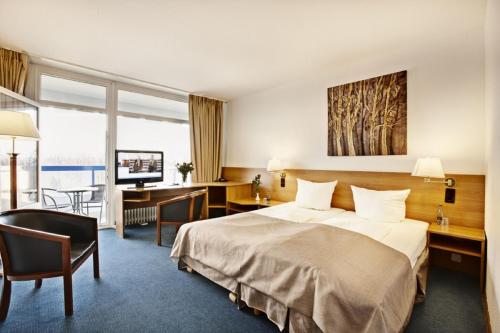プレーンにあるHotel Plöner See by Tulip Innのベッドとデスクが備わるホテルルームです。