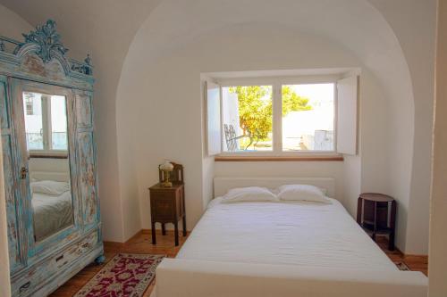 a bedroom with a bed and a window and a mirror at CASA AMARELA in Avis