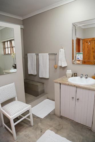 a bathroom with a sink and a chair and a mirror at 5 Konings Guesthouse in Paarl