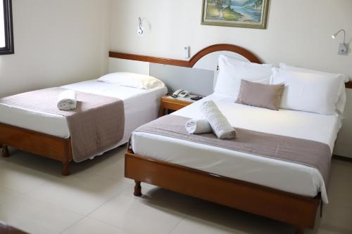 a hotel room with two beds and a night stand at Champagnat Praia Hotel in Vila Velha