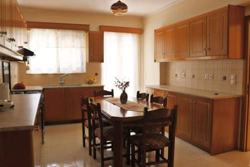 a kitchen with wooden cabinets and a table and chairs at Entire large house Apollon in Voládha