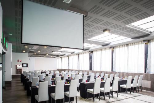 a conference room with tables and chairs and a large screen at Gran Hotel Luna de Granada in Granada