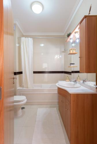 a bathroom with a sink and a tub and a toilet at Apartamento Praia São Martinho do Porto in São Martinho do Porto