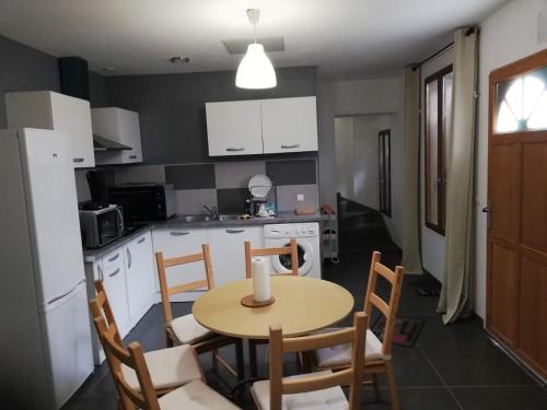 une cuisine avec une table et des chaises et une cuisine avec des armoires blanches dans l'établissement Maison Duplex & Appartement sur cour, à La Ferté-Gaucher