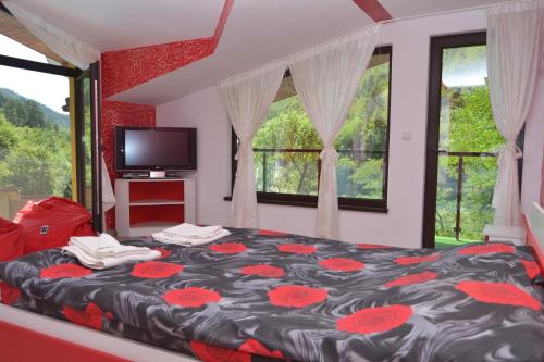 Къща за гости Суни Транс في سموليان: غرفة نوم مع سرير مع زهور حمراء عليه