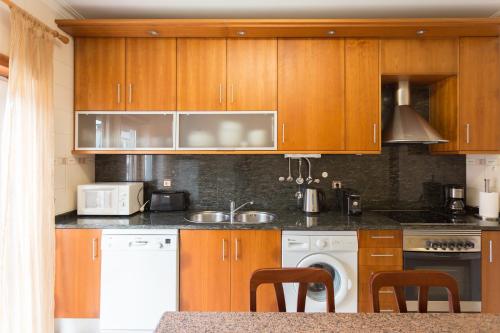 - une cuisine avec des placards en bois et des appareils blancs dans l'établissement Apartamento Praia São Martinho do Porto, à São Martinho do Porto