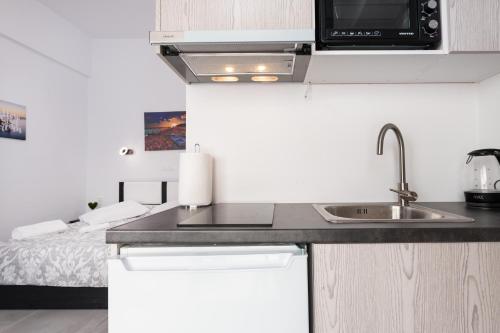a small kitchen with a sink and a bed at Akrogiali Apartments in Barbati