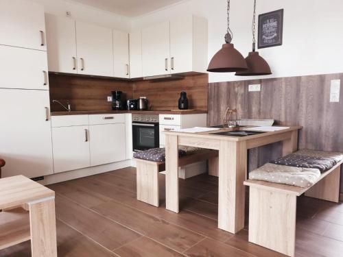 a kitchen with white cabinets and a wooden table at Ferienhausgebiet Oberlangen in Oberlangen