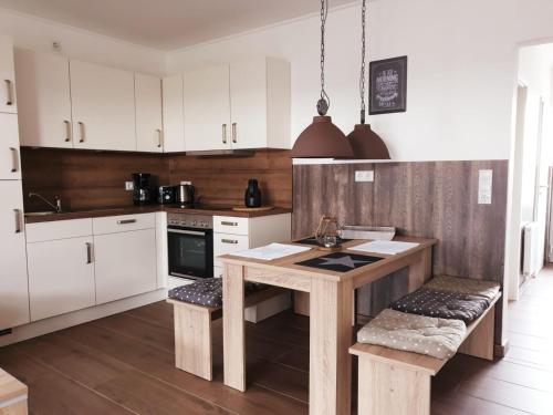 a kitchen with white cabinets and a wooden table with benches at Ferienhausgebiet Oberlangen in Oberlangen