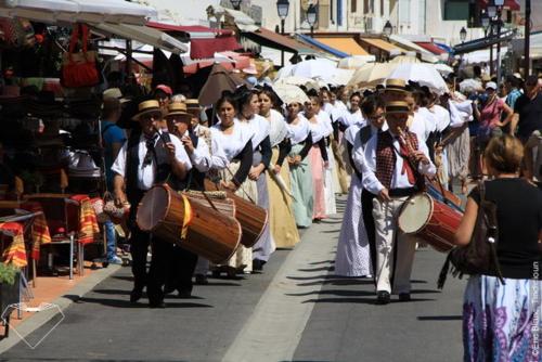 a group of people walking down a street with drums at Hôtel Le Neptune en Camargue in Saintes-Maries-de-la-Mer