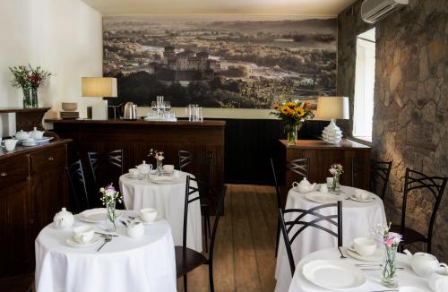 un restaurante con mesas y sillas blancas y una pintura en La Locanda del Borgo en Torrechiara