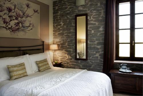 um quarto com uma cama branca e uma parede de pedra em La Locanda del Borgo em Torrechiara