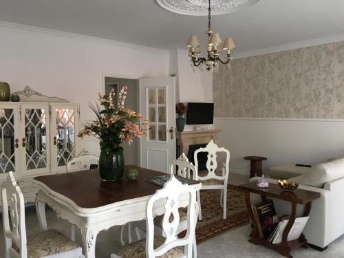 een eetkamer met een tafel en witte stoelen bij Casa do gato branco in Furadouro