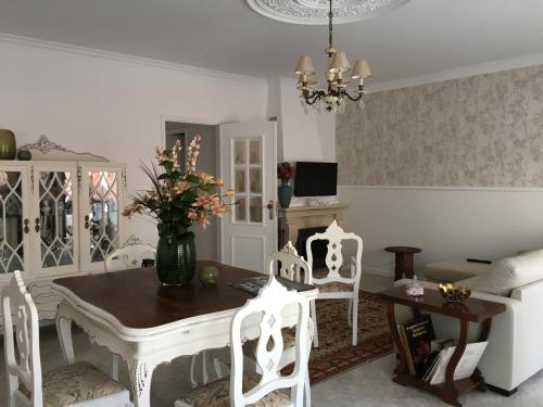a dining room with a table and white chairs at Casa do gato branco in Furadouro